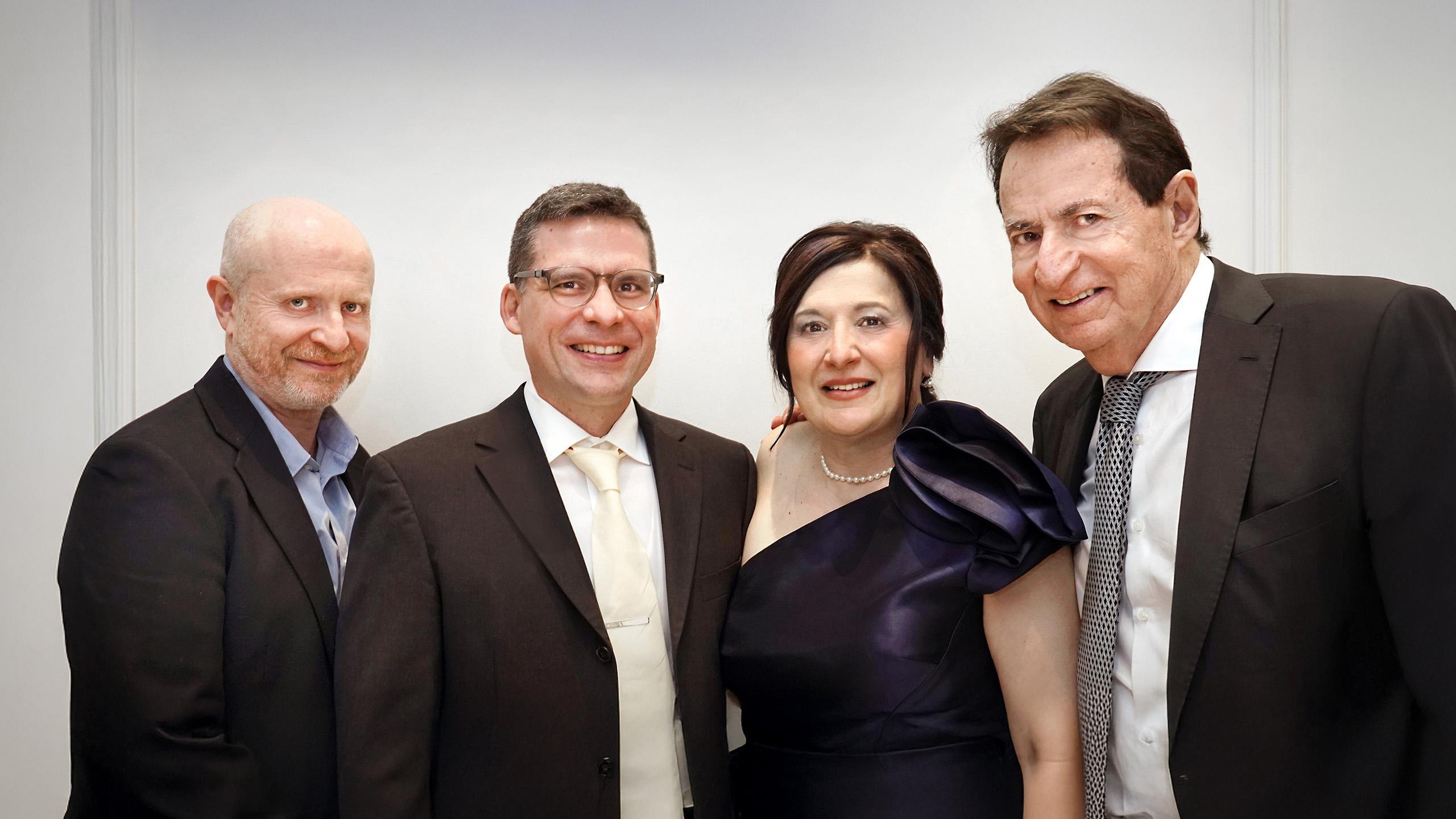 three men and one woman stand smiling