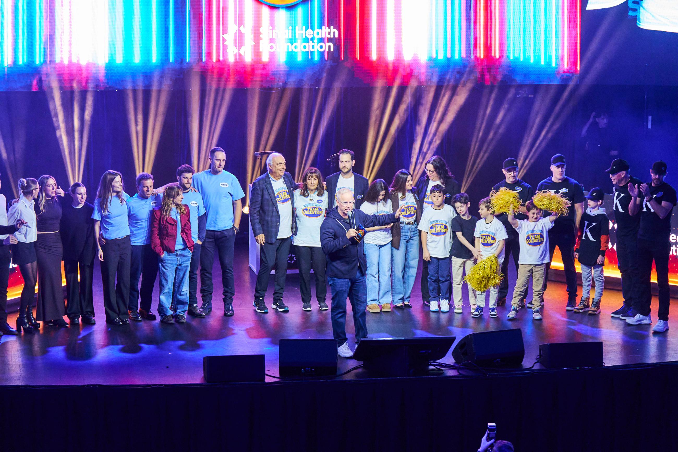 large group stands on stage, celebrating their win