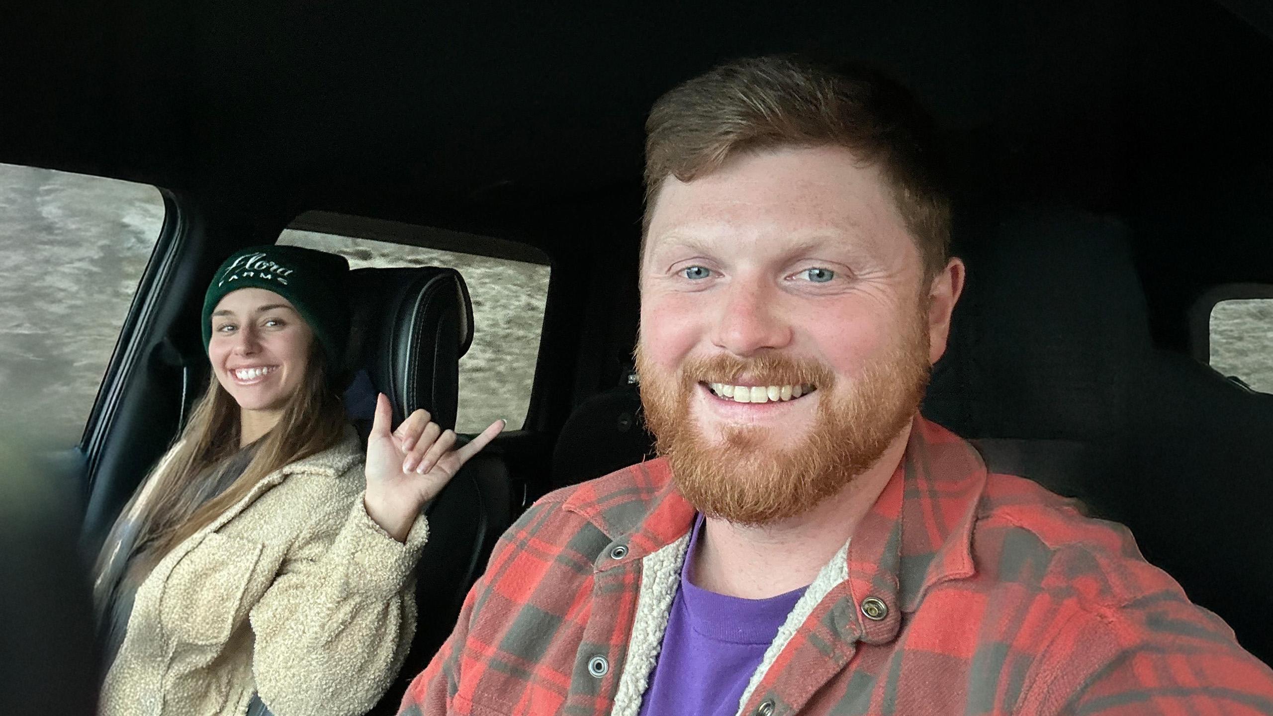 Man sits in drivers seat of car with wife sitting in passenger seat