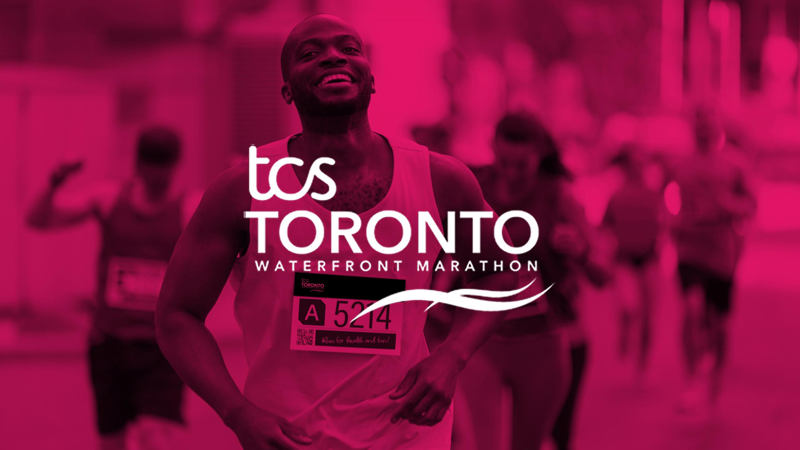 A man smiling while running in a marathon with the white logo that says TCS Toronto Waterfront Marathon