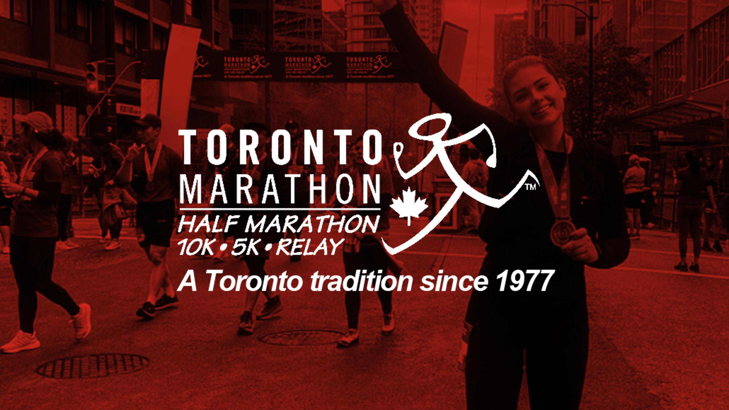 Runners cross a downtown Toronto finish line during the Toronto Marathon, with one participant raising a medal and event branding reading “Toronto Marathon — Half Marathon, 10K, 5K, Relay — A Toronto tradition since 1977.