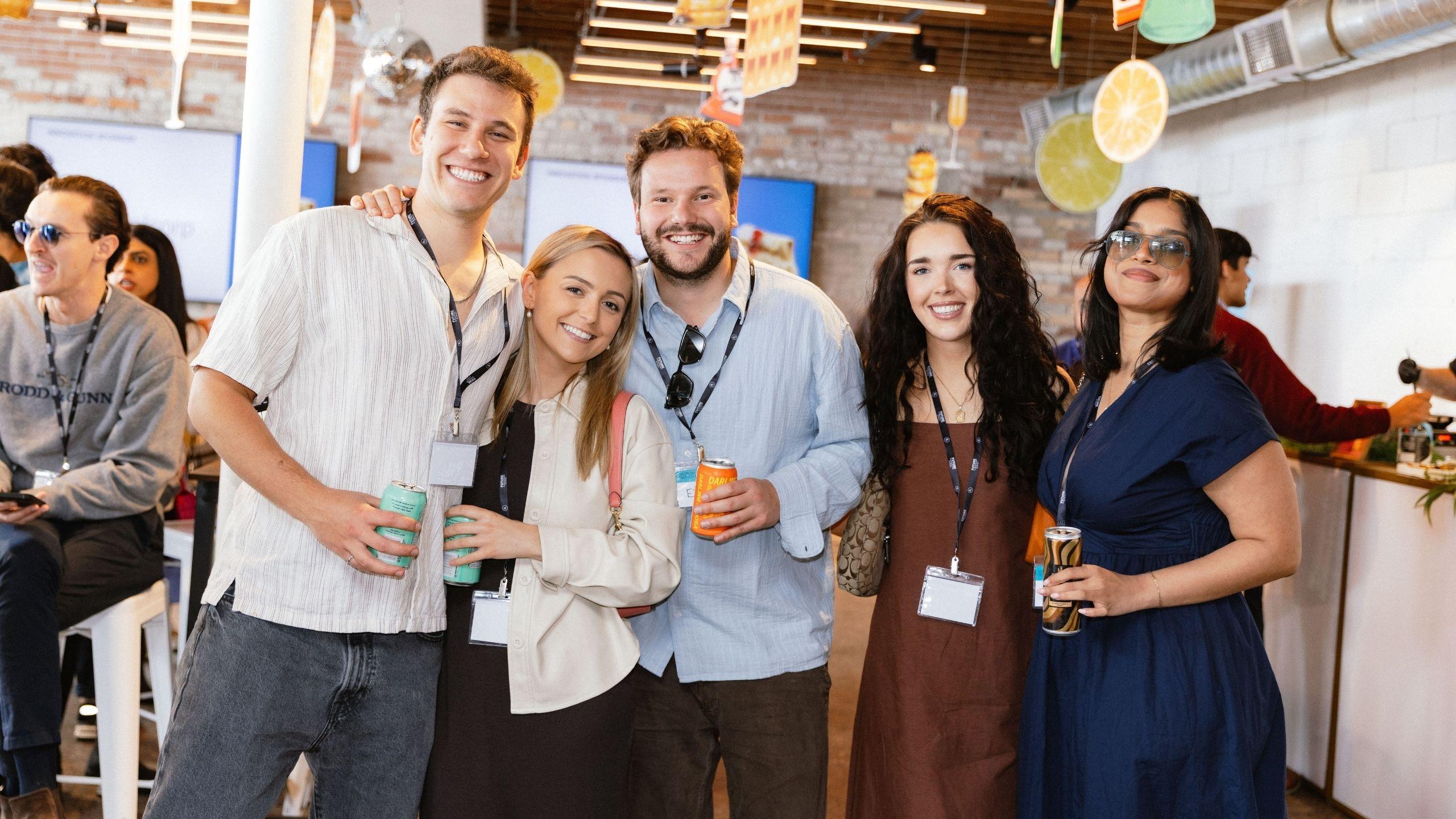 Group of five people in smart brunch attire, smiling with their arms around each other at the Discovery Brunch event