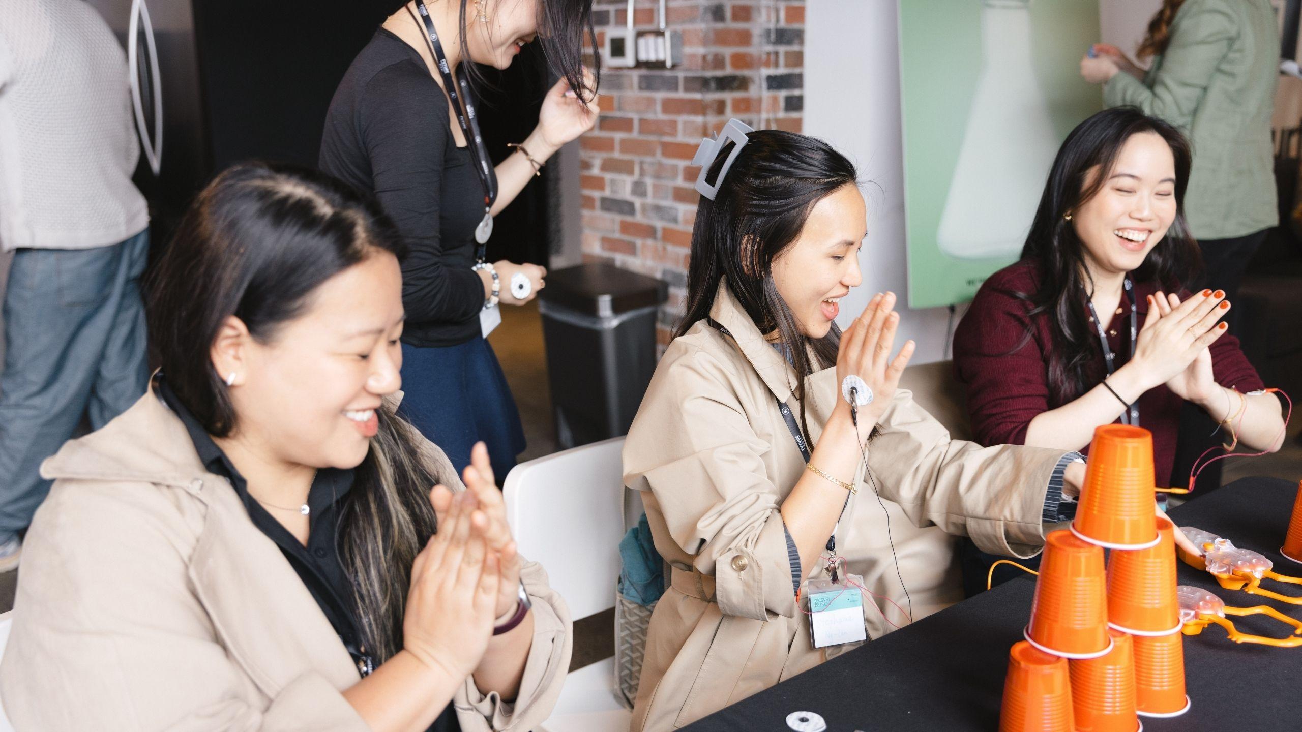 A group of three women smiling while participating in research learning activity at discovery brunch
