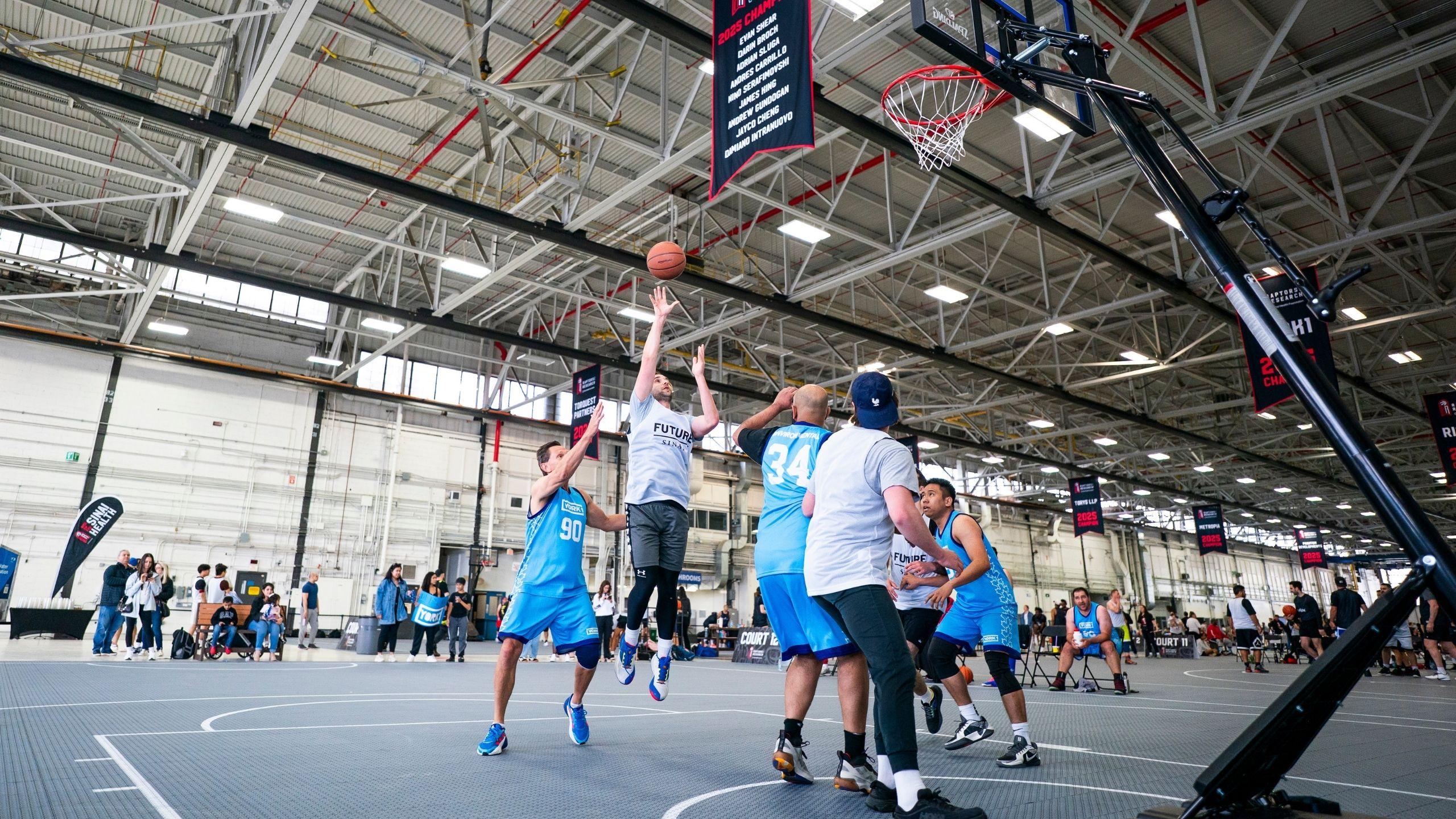 Action shot of a 4-on-4 basketball game, with a Future Sinai team member mid-jump releasing the ball toward the basket as defenders look on