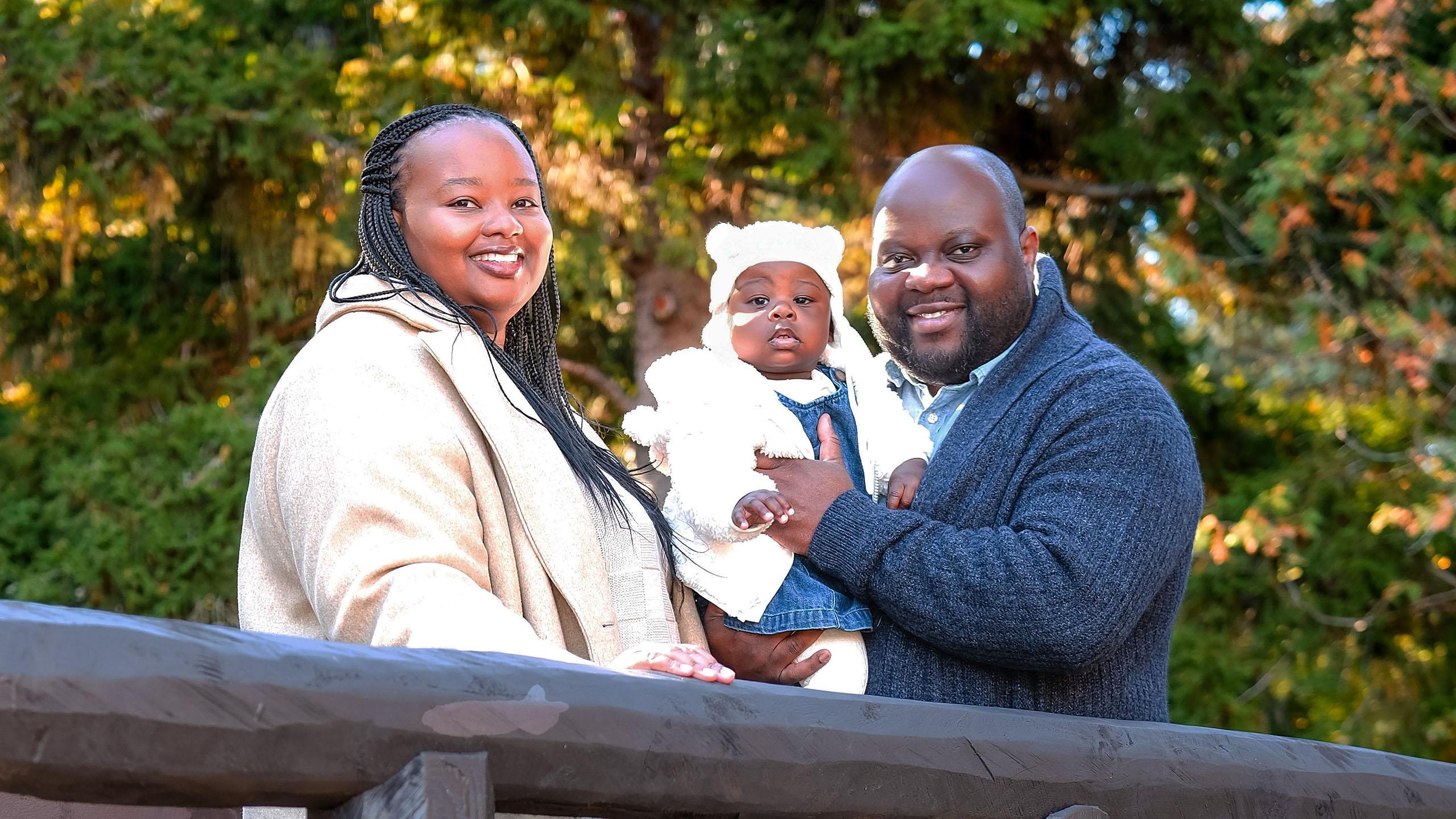 mother, father and baby smile on a bridge outside