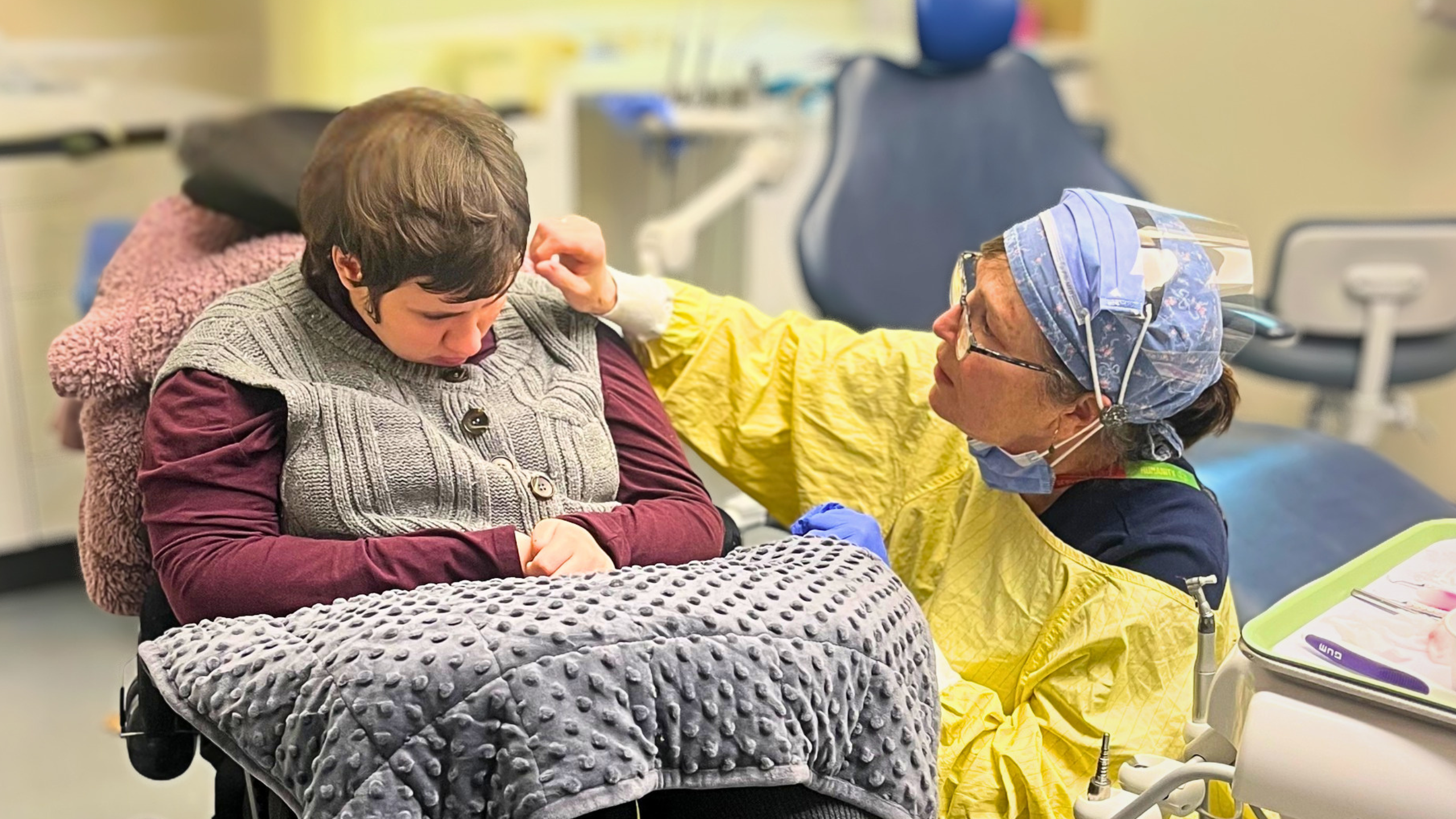 Patient receiving supportive dental care from clinician using calming sensory techniques