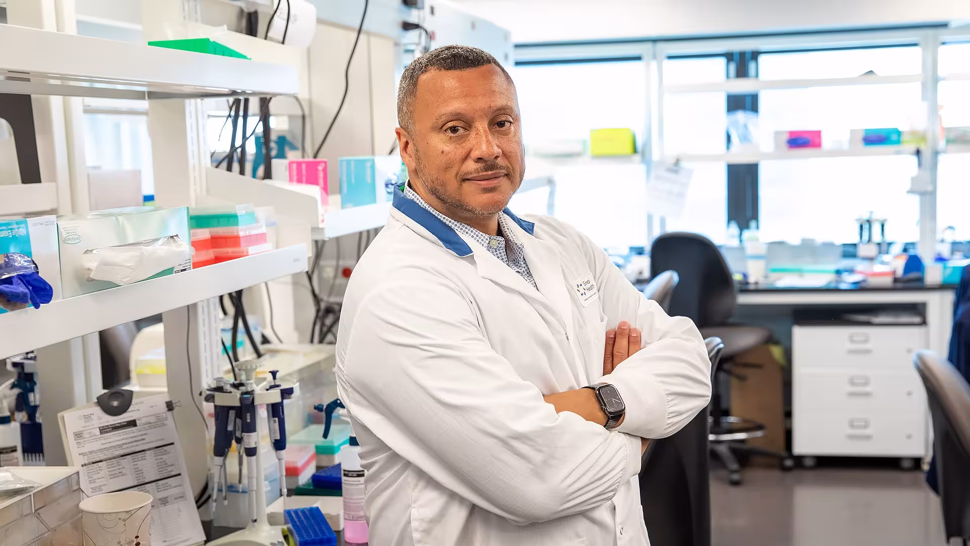Dr. George Charames in a white lab coat standing in a laboratory.