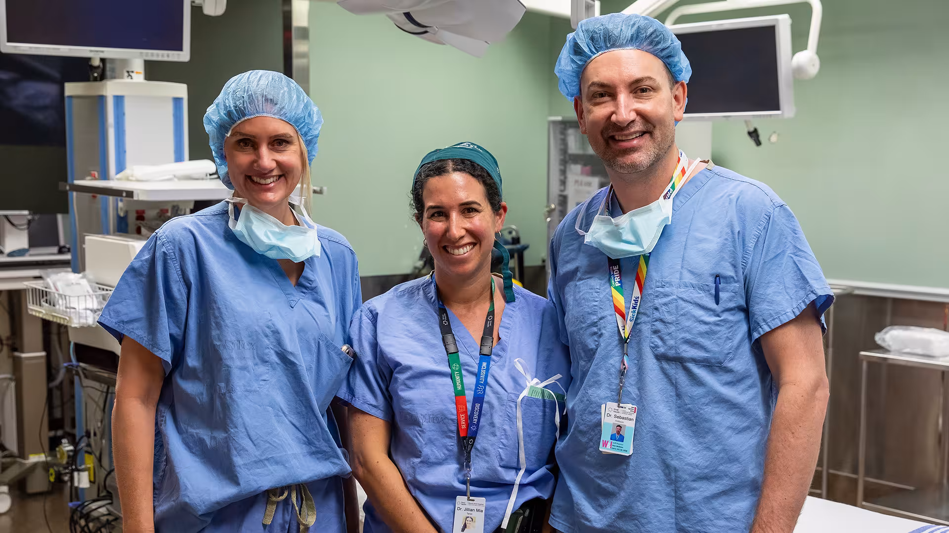 Three people standing in an operating room smiling.