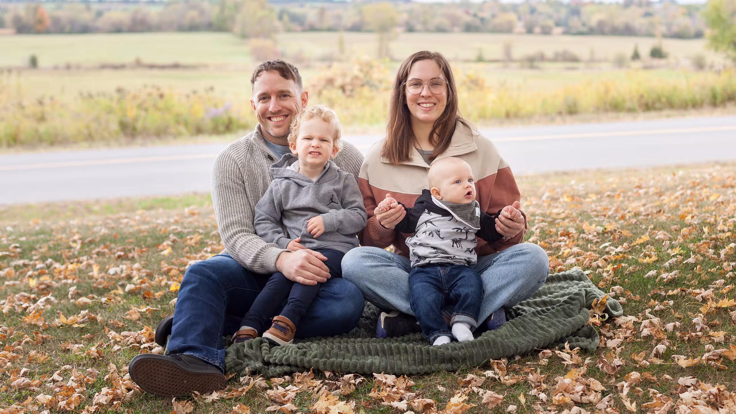 family sits on a blanket in a field