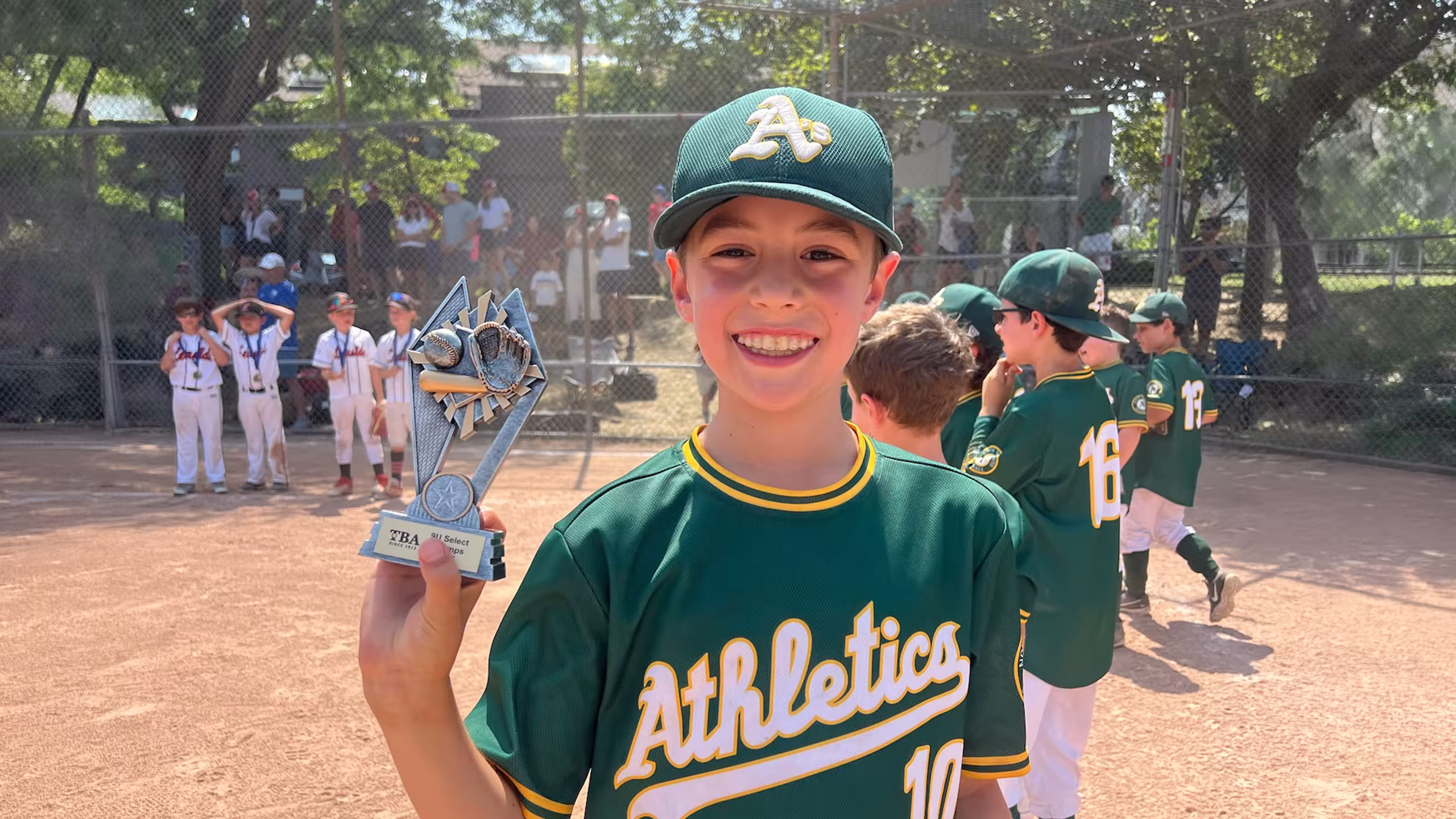 young baseball player holding trophy