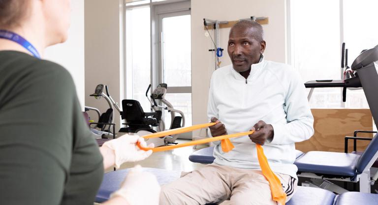 Mr. Solomon using yellow bands during rehab session.