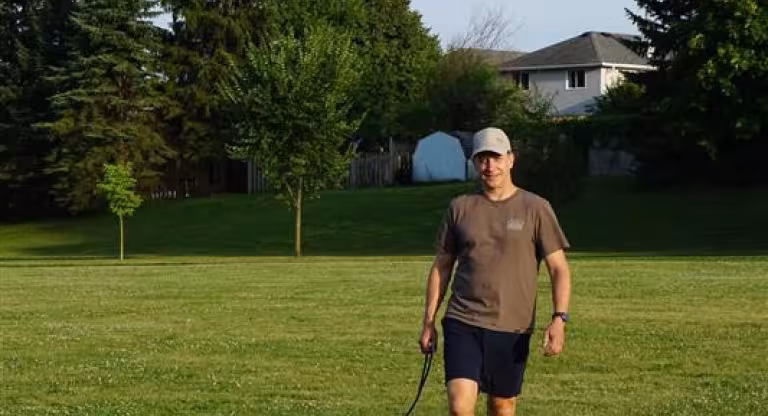 man walking in a field with dog