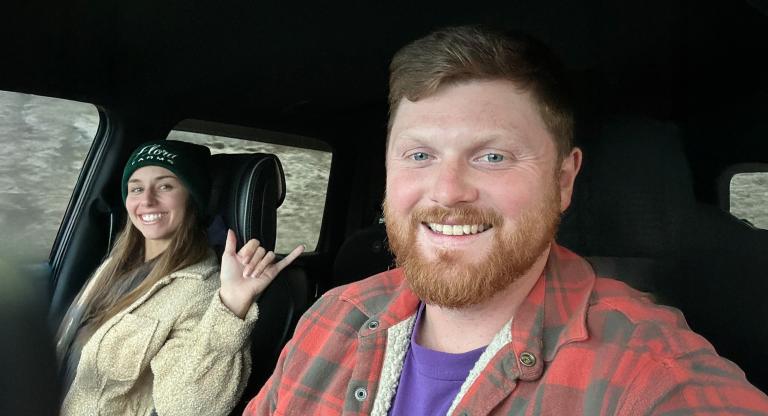 Man sits in drivers seat of car with wife sitting in passenger seat