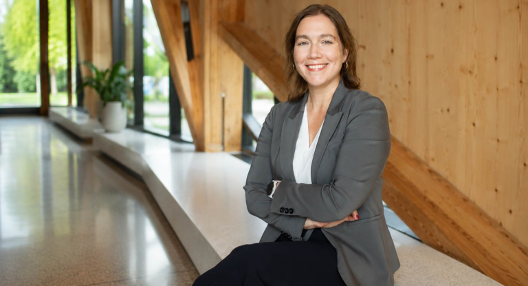 A woman sits on a bench with a smile on her face.
