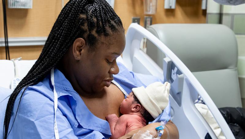 New mother holding her baby in a hospital bed.