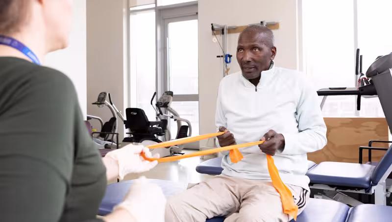 Mr. Solomon using yellow bands during rehab session.