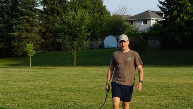 man walking in a field with dog