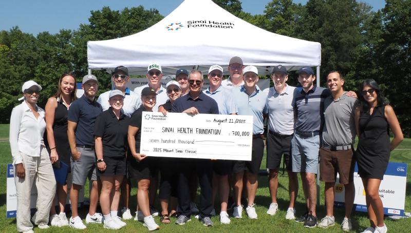 group stands outside holding presentation cheque
