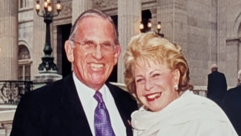 Smiling man and woman. Red banner with white text reads Jerry and Carole Grafstein
