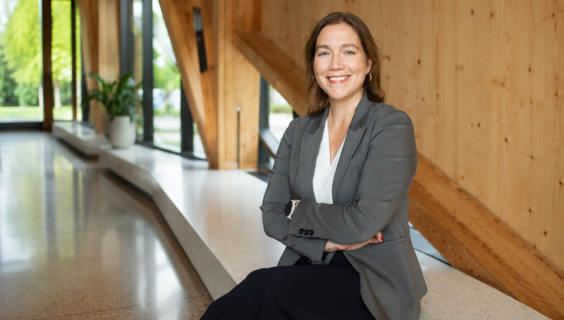 A woman sits on a bench with a smile on her face.