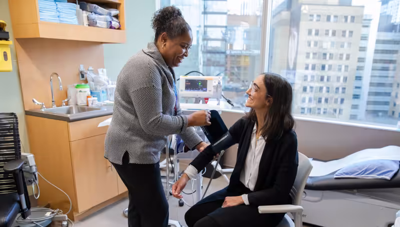 patient sits in chair while care provider takes blood pressure