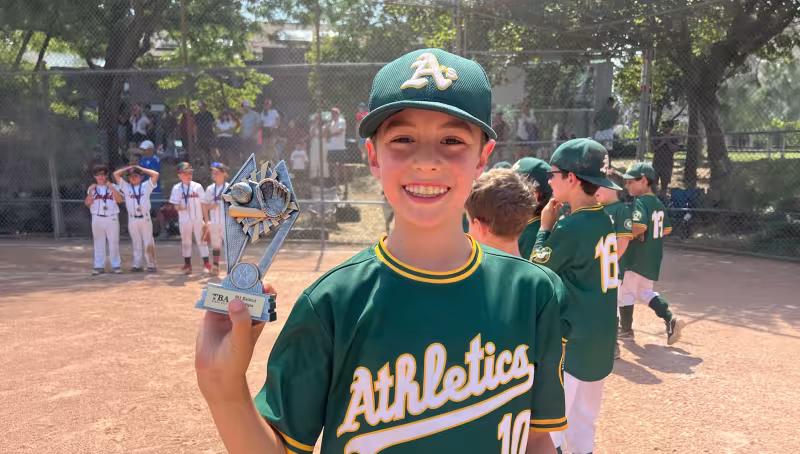 young baseball player holding trophy