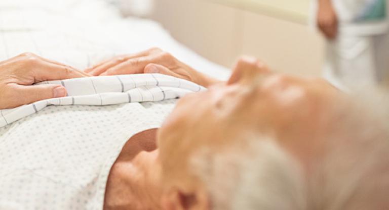 A senior man lying in a hospital bed