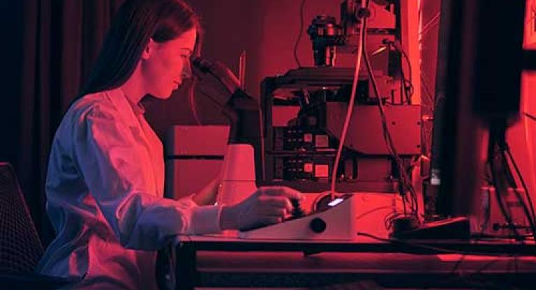 Woman sits in front of a microscope