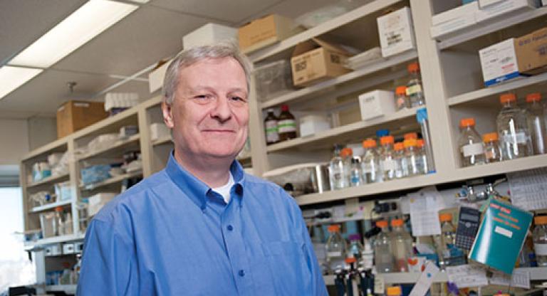 Man in blue button-up shirt stands in a medical lab