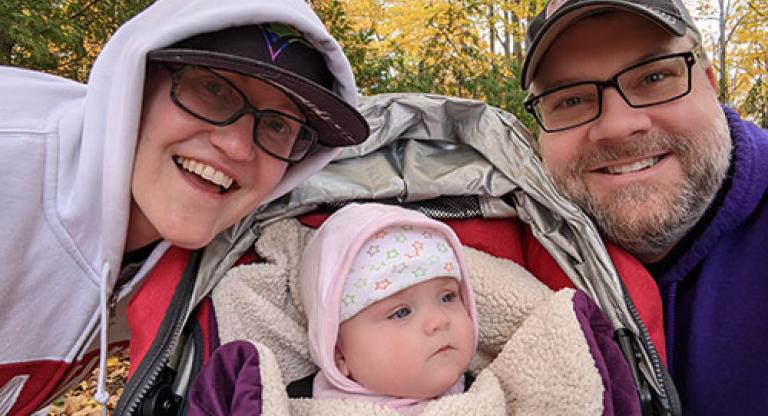 A mother and a father smile with their baby.
