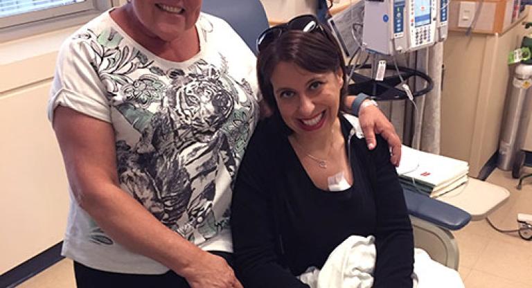 Two smiling women sit on a treatment chair.