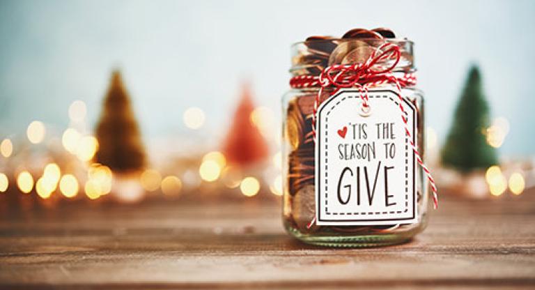 Masons jar full of coins, with a label that says, "'tis the season to give"