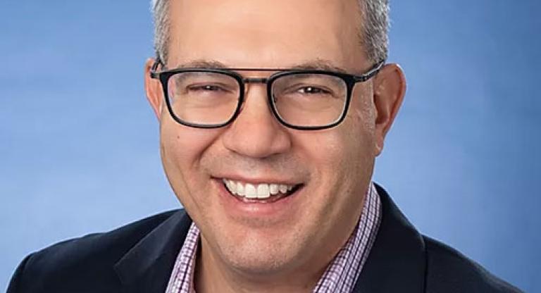 headshot of smiling man wearing glasses