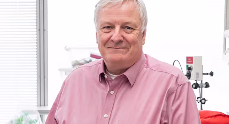 A man with white hair smiling