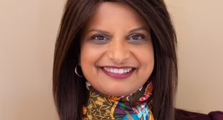 A smiling woman with long hair wearing a colourful scarf.