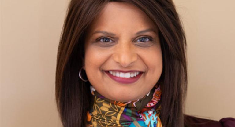 A smiling woman with long hair wearing a colourful scarf.