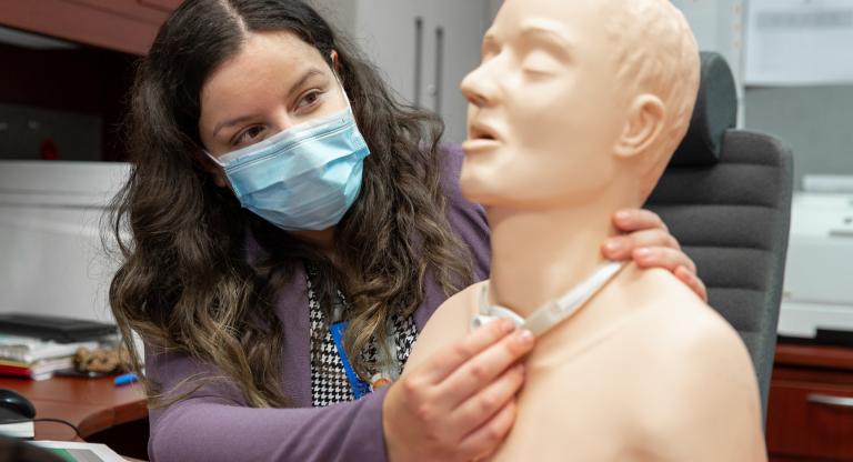 Sarabeth Silver holds a mannequin used for tracheostomy education