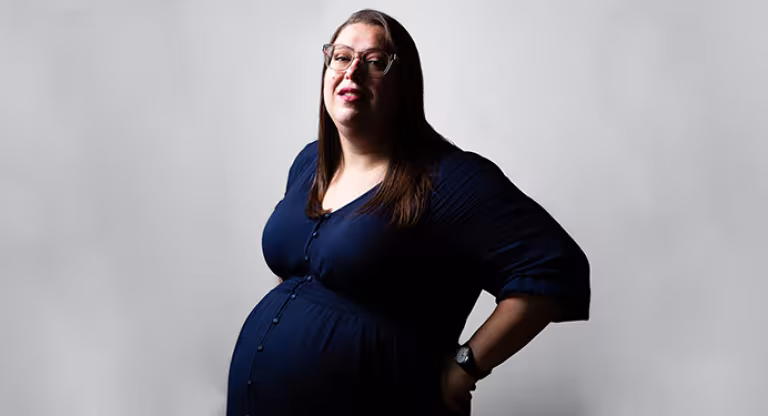 a bespectacled and visibly pregnant woman