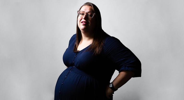 a bespectacled and visibly pregnant woman