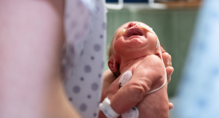 Newborn baby being held in someone's hands 