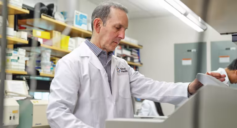 Dr. Daniel Drucker operating a lab instrument. He is wearing a white lab coat