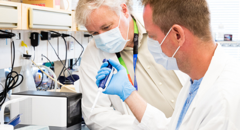 Dr. Jeff Wrana observes a colleague performing a test in the lab.