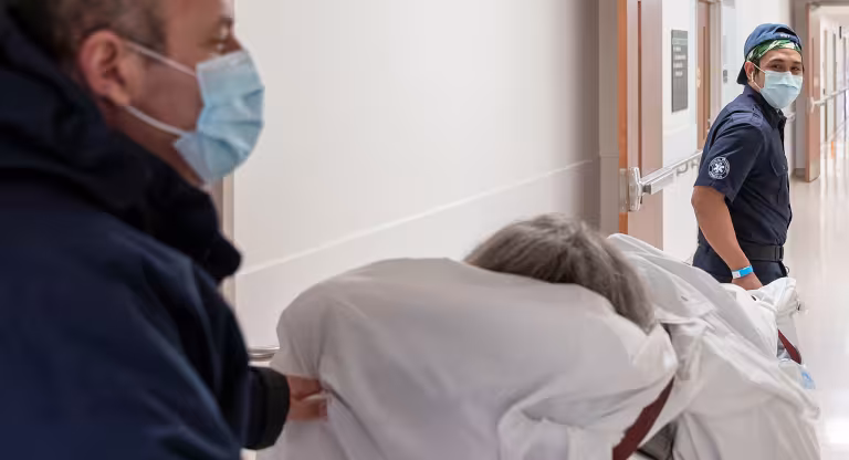 Two people transport a patient down a hallway at Bridgepoint Active Healthcare.