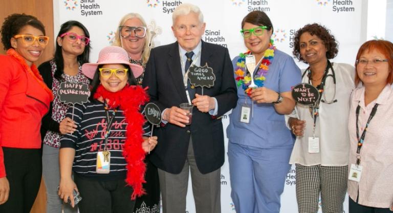 A group of people pose with props from a photo booth.
