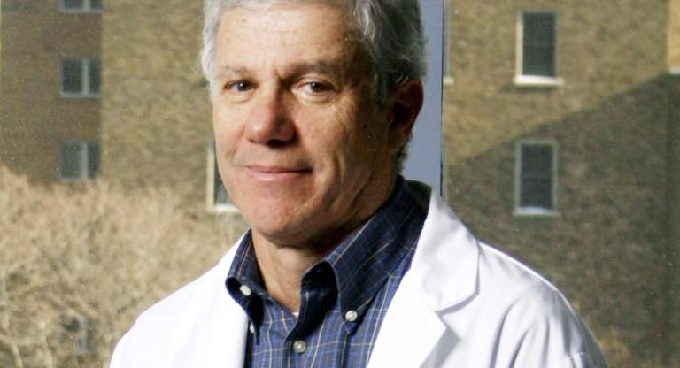 A man in a lab coat with a building in background