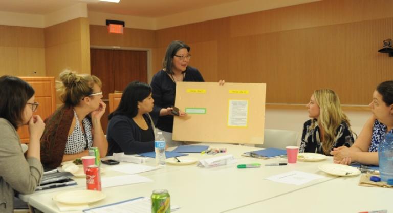 A group of people at a table looking at a board held by a person