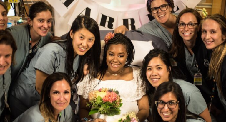 Nurses with patient in wedding dress and bouquet of flowers.
