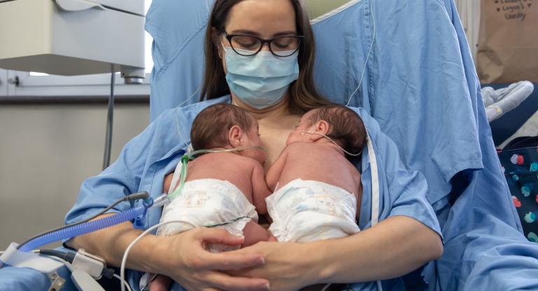 A mother breastfeeding her twin babies