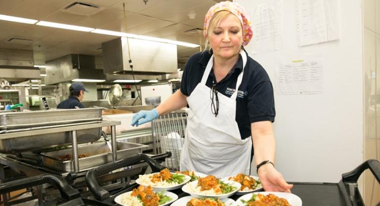 Jessica Godin, Manager, Patient Food Services, giving out plates of food in the Mount Sinai kitchen.