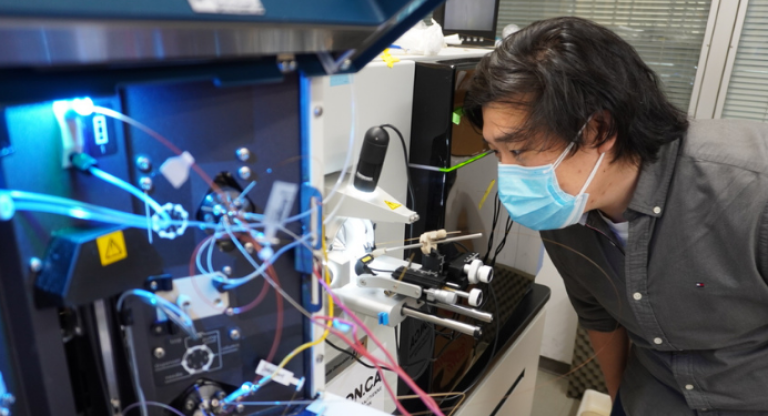 researcher examining a specimen through a microscope